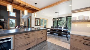 Una cocina moderna con una isla grande, armarios de madera e iluminación colgante.