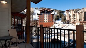 A balcony with a view of a ski resort, including a building with multiple floors and a parking area. - Peregrine Point Condo by the Main Plaza - Walk to Slopes (Durango)