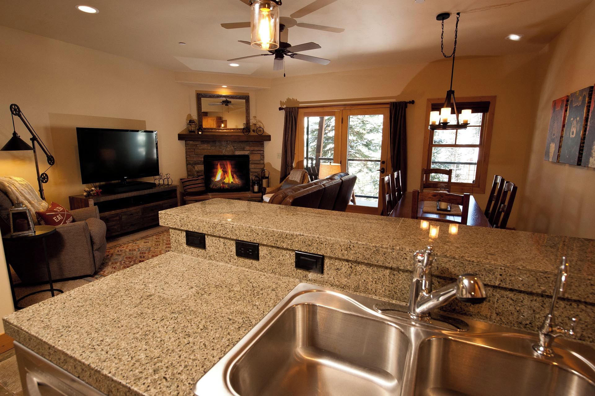 A modern kitchen with granite countertops, a stainless steel sink, and a fireplace.