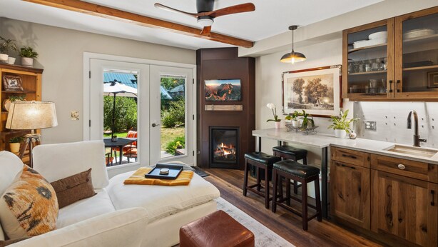 A modern kitchen with a fireplace, wooden cabinets, and a dining area with a view. - Western Way | Patio Facing Mountains & River (Telluride)