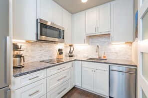 Enjoy cooking in this well-equipped kitchen with a granite countertop, mosaic backsplash, and modern appliances.