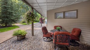 An outdoor patio with a table and chairs, surrounded by a gravel path and greenery. - Cozy Viking Lodge 105: One-bedroom escape with hot tub access (Telluride)