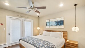 A bedroom with a bed, a ceiling fan, a wall-mounted artwork, and a bedside table. - Cozy Viking Lodge 105: One-bedroom escape with hot tub access (Telluride)