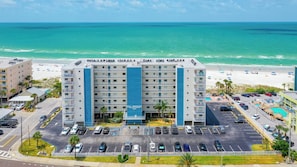 Un hotel de varios pisos con una torre azul central, aparcamiento y vistas a la playa.