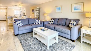 A modern living room with two sofas, a coffee table, and a dining area in the background.