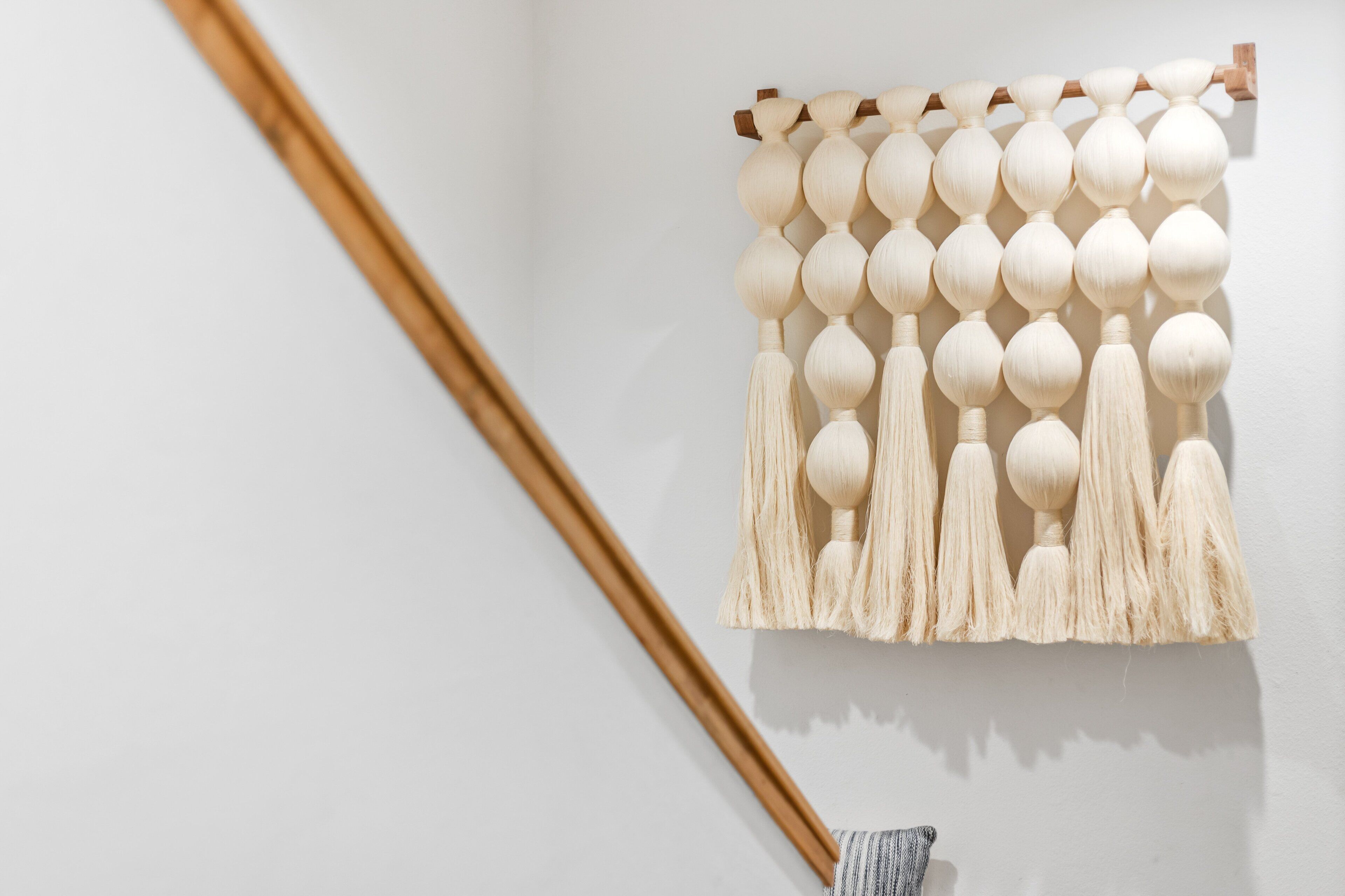 Een macramé wanddecoratie met bolvormige en fransen details.