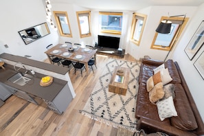 A modern kitchen with a dining area, a sofa, and a fireplace.