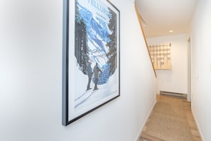 A hallway with a framed poster of a skier on a mountain.
