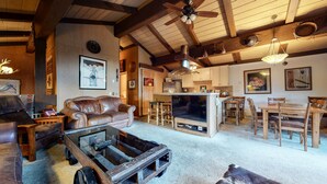 Un salon au style rustique, avec un canapé en cuir, une table basse en bois et un téléviseur.