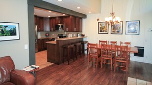 Una cocina moderna con armarios de madera, una isla central con taburetes y un comedor con sillas de madera.