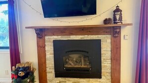 Una chimenea con revestimiento de piedra, un televisor montado encima y una decoración con forma de oso a la izquierda.