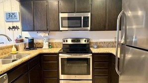 Una cocina moderna con armarios oscuros, electrodomésticos de acero inoxidable y una encimera de granito.