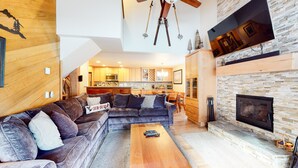 A spacious living area with a sectional sofa, a fireplace, and a kitchen in the background. - Deluxe, Remodeled Condo in a Quiet Location. Near Biking Trails & Lakes Basin (Mammoth Lakes)