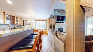 A modern kitchen with a long counter, wooden cabinets, and a stone backsplash. - Deluxe, Remodeled Condo in a Quiet Location. Near Biking Trails & Lakes Basin (Mammoth Lakes)