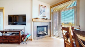 Una sala de estar con chimenea, televisor y comedor con muebles de madera.