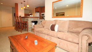 A living room with a beige sofa, a wooden coffee table, and a remote control on it.