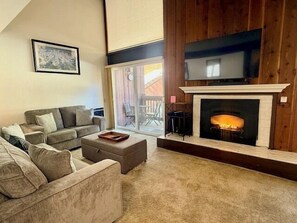 A living room with a fireplace, a sofa, a coffee table, and a television mounted above the fireplace. - Mammoth Ski & Racquet Club #120 - Pet Friendly (Mammoth Lakes)