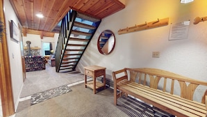 Una escalera de madera que conduce a una zona tipo entrepiso con un sofá y una mesita.