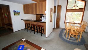 Eine Küche mit Holzausstattung, einer Bar und einem Esstisch mit Stühlen.