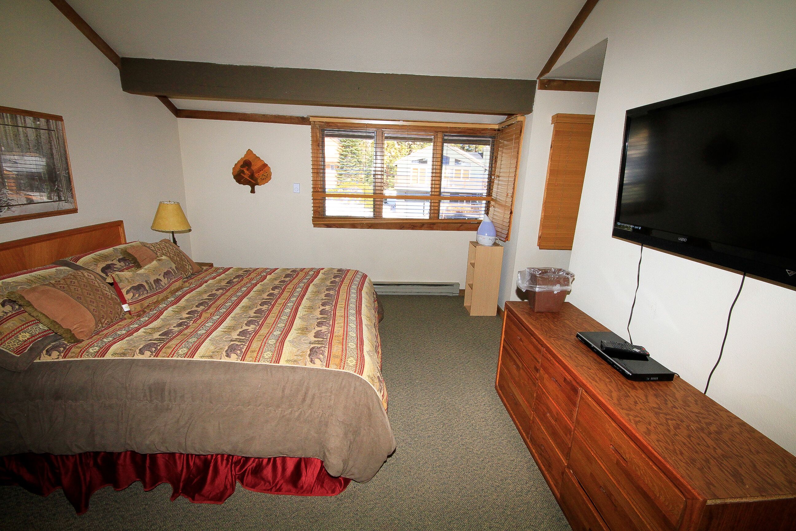 Une chambre à coucher avec un lit, une télévision, une fenêtre et une commode.