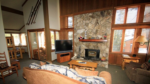 A cozy living room with a stone fireplace, wooden furniture, and a television. - Mountainback #63, Loft, Den (Mammoth Lakes)