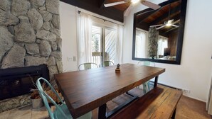 A dining area with a wooden table and chairs, a stone wall, and a large mirror. - Mountain Rustic, Pool & Tennis, Near Dining, Rec Center, Bowling & Trails (Mammoth Lakes)