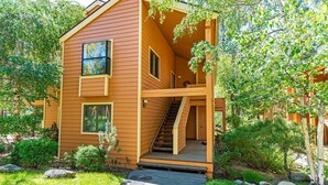 A two-story wooden house with a staircase leading to a balcony, surrounded by lush greenery. - 107 McCloud 2BR/2BA Incline Village w/ Hot Tub (Incline Village)