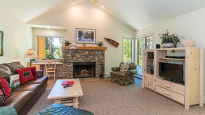A cozy living room with a stone fireplace, a leather sofa, a wooden coffee table, and a TV cabinet. - 107 McCloud 2BR/2BA Incline Village w/ Hot Tub (Incline Village)