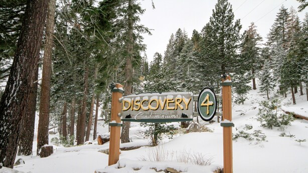 A wooden sign with the text "Discovery Condominiums" and a directional arrow.