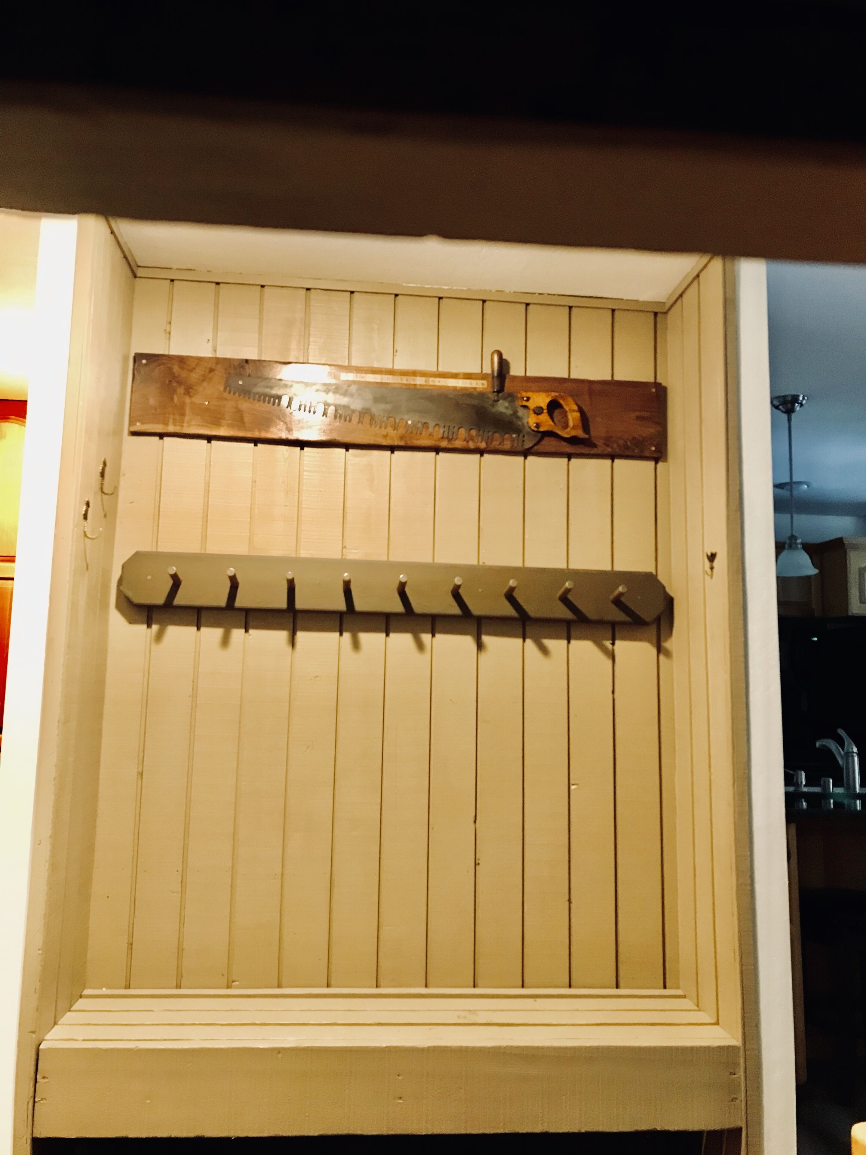 Paret de fusta amb una serra metàl·lica i un panell picat.