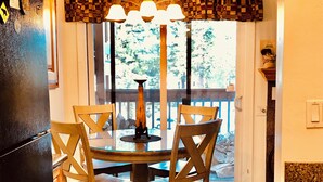 A kitchen with a dining table, chairs, a chandelier, and a view of the outdoors.