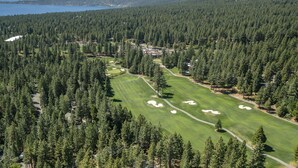 Eine Vogelperspektive eines Golfplatzes, der von dichtem Wald umgeben ist, mit freiem Blick auf die Spielbahn und die Sandbunker.