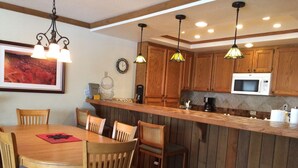 Una cocina con armarios de madera, un microondas y un comedor con una mesa y sillas.