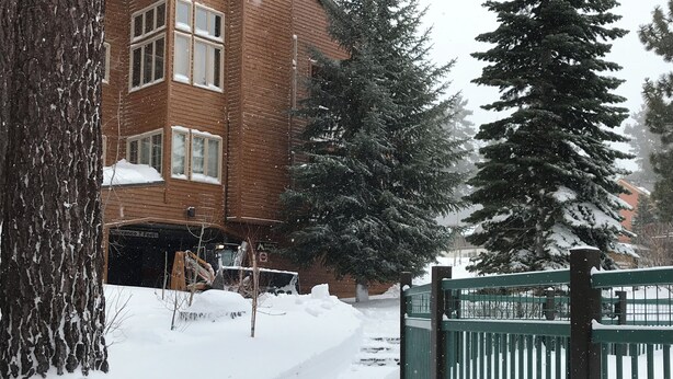 Un sendero cubierto de nieve que lleva a un edificio con una valla verde.
