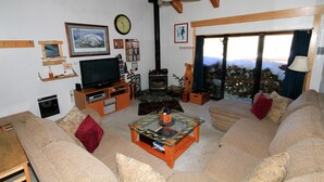 A cozy living room with a television, fireplace, and large windows. - Courchevel #51 2 Bedroom 2 Bath (Mammoth Lakes)