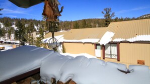 A bed with snow piled on it, a wooden sculpture, and a building with a snow-covered roof in the background. - Courchevel #51 2 Bedroom 2 Bath (Mammoth Lakes)