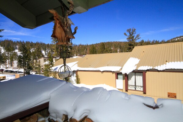 A bed with snow piled on it, a wooden sculpture, and a building with a snow-covered roof in the background. - Courchevel #51 2 Bedroom 2 Bath (Mammoth Lakes)