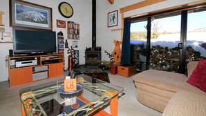 A living room with a television, bookshelves, a fireplace, and a large window. - Courchevel #51 2 Bedroom 2 Bath (Mammoth Lakes)