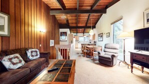 A cozy living room with a wooden ceiling, a sofa, a coffee table, and a TV. - Spacious Condo, Near Biking Trails. Great Summer Amenities & Pool On-site (Mammoth Lakes)