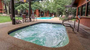 A hot tub area with a pool, surrounded by lounge chairs and a covered patio. - Spacious Condo, Near Biking Trails. Great Summer Amenities & Pool On-site (Mammoth Lakes)