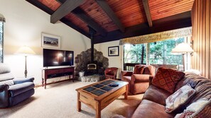 A cozy living room with a stone fireplace, a television, a comfortable sofa, and a coffee table.