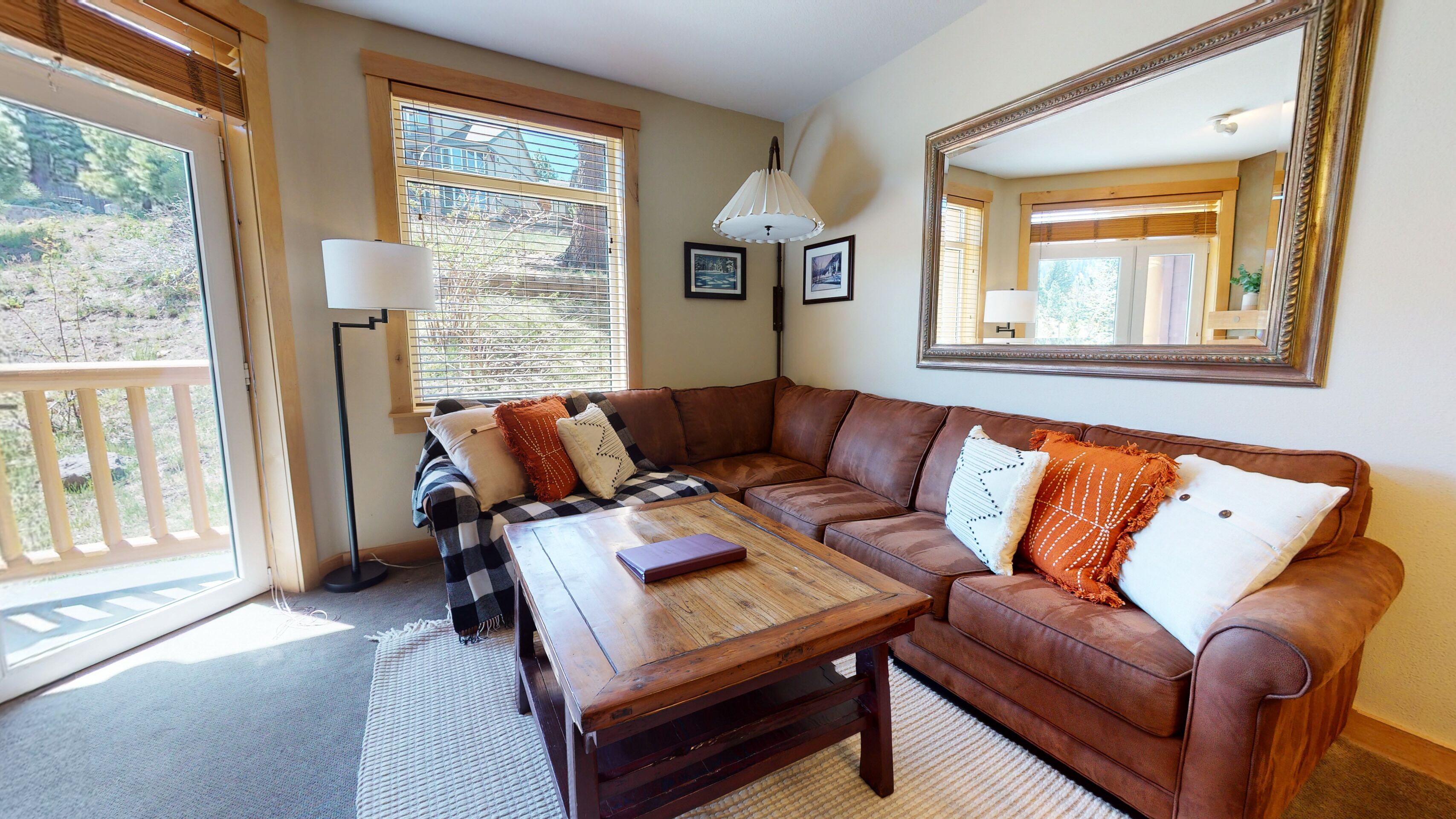 Ein gemütliches Wohnzimmer mit einem braunen Ledersofa, einem Holztisch und einem großen Spiegel an der Wand.