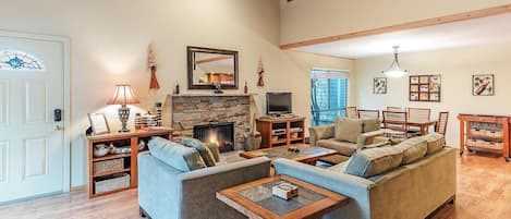 A spacious living room with a fireplace, sofas, and a dining area.