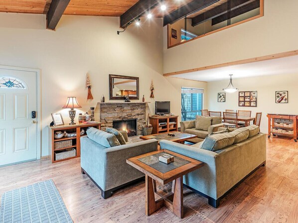 A spacious living room with a fireplace, sofas, and a dining area.