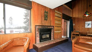 A room with a fireplace, leather chairs, and a view of the outdoors. - Mammoth Ski & Racquet Club #129, 1 Bdrm + Loft (Mammoth Lakes)