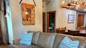 A living room with a sofa, decorative mirror, antler wall art, and a chandelier. - Mountainback #79, Loft, Den (Mammoth Lakes)