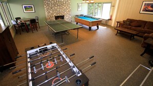 Amplia sala de estar con mesa de fútbol, mesa de billar y un rincón de descanso acogedor con sofá y sillones.