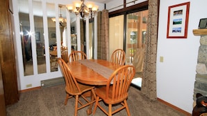A dining area with a wooden table and chairs, a chandelier, and a view through a glass door. - Discovery 4 #113 1 Bedroom 1 Bath (Mammoth Lakes)