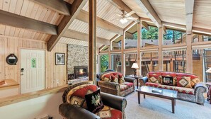 A spacious lodge with wooden beams, a stone fireplace, leather sofas, and a view of the surrounding forest. - 10NSE | 3BR/2.5BA Incline Village, Mtn Views & BBQ (Incline Village)