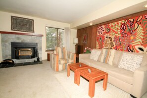Relax in a cozy space with a fireplace, sofa, and vibrant mural.